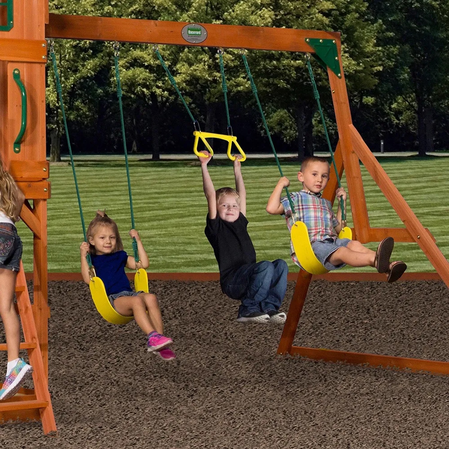 Kinder spielen auf dem Backyard Discovery Spielturm Atlantic mit Schaukel und Trapezstange.