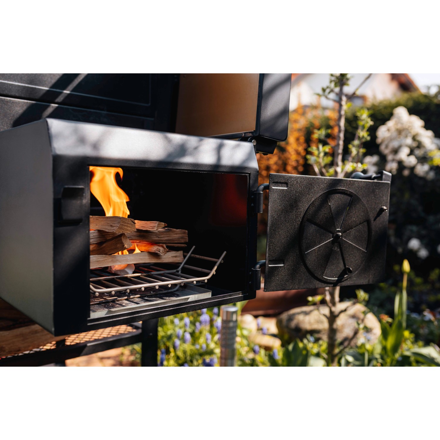 Jamestown Kombigrill Drake Holzkohlegrill mit Feuerholz und geöffneter Tür.
