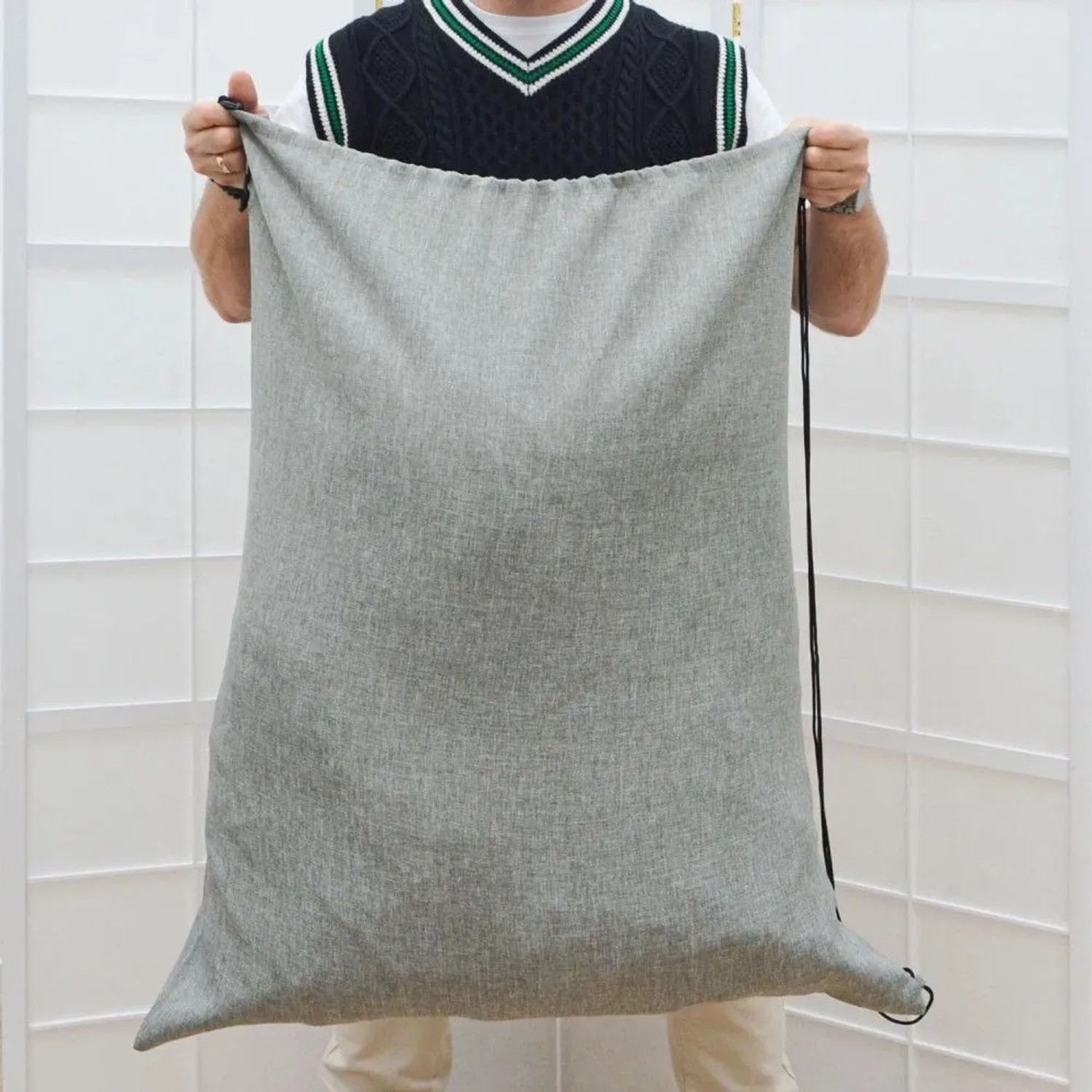 Großer grauer Wäschesack mit Leinenoptik und Kordelzug, von Person gehalten. Wäschesammler für 100 Liter Wäsche.