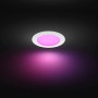 Weißer Philips Hue Einbauspot Slim mit farbigem Licht an dunkler Decke.