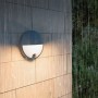 Anthrazitfarbene Philips LED-Außenwandleuchte Capricorn mit Bewegungssensor an Ziegelwand im Regen. Warmweißes Licht.