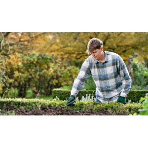 Mann benutzt Bosch Garten-Grubber zur Bodenbearbeitung im Gartenbeet.