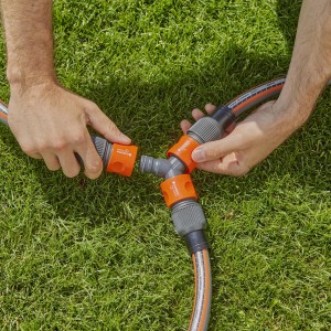 Gardena Profi-System Y-Stück für Schlauchabzweigung im Garten, montiert von zwei Händen.