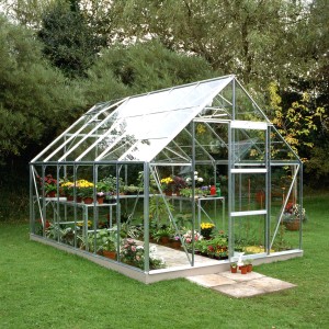 Helles Halls Gewächshaus Universal 128 aus Alu mit Pflanzen und Fundamentrahmen im Garten.