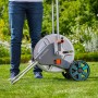 Gardena CleverRoll M Metall Schlauchwagen mit Person auf Rasen. Gartenschlauchwagen mit Metalltrommel und Rädern.