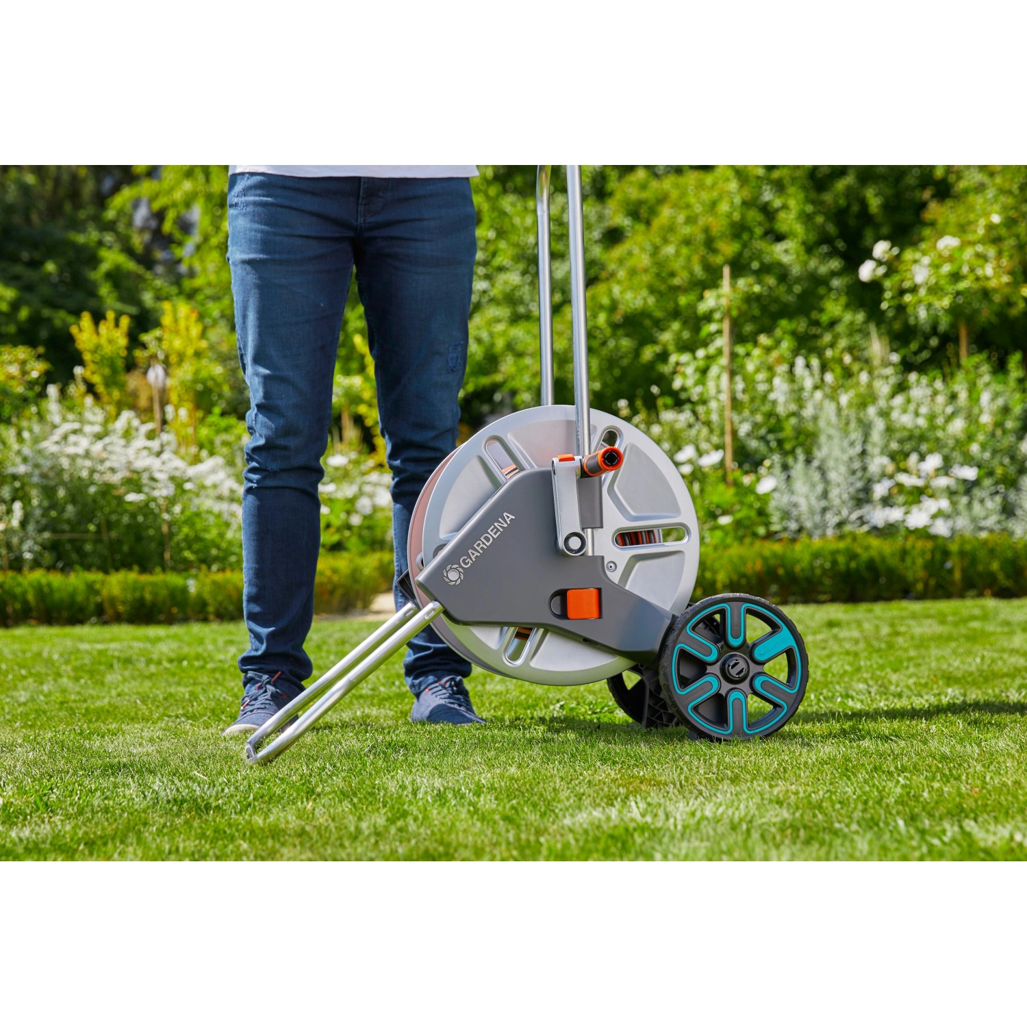 Gardena CleverRoll M Metall Schlauchwagen mit Person auf Rasen. Gartenschlauchwagen mit Metalltrommel und Rädern.