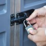 Detailaufnahme: Person verschließt ein anthrazitfarbenes Palram Gerätehaus mit Vorhängeschloss.