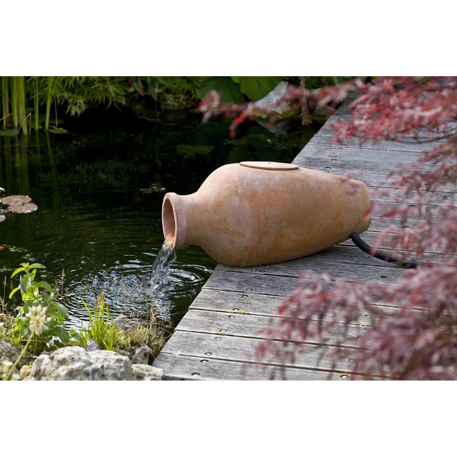 Terrakottafarbene Acqua Arte Amphora I als Teichfilter und Wasserspiel im Garten.