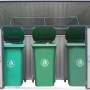 Graue Metall Mülltonnenbox für 3 Tonnen à 240L, mit geöffneten Türen und grünen Tonnen.