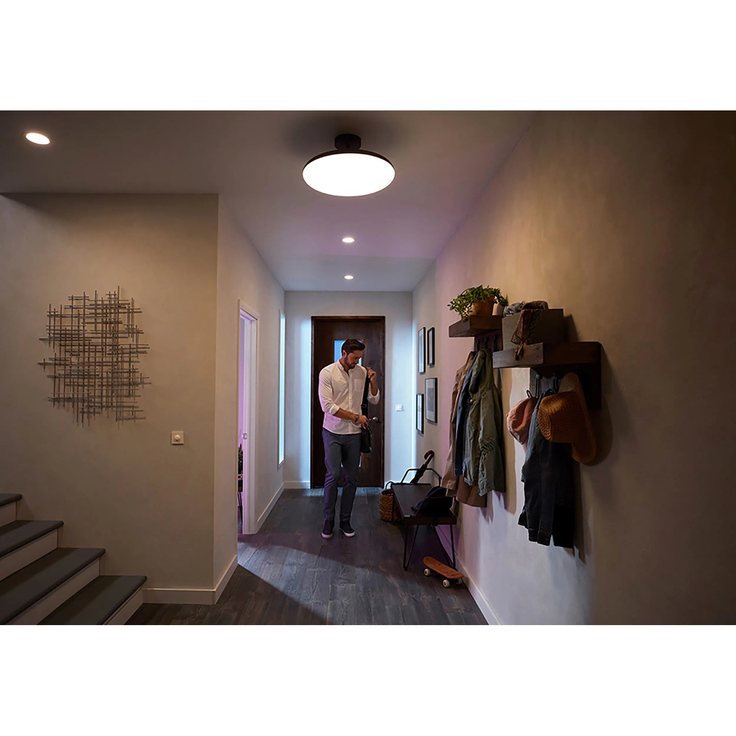 Szene mit Philips Hue Centura Einbauspots: Mann im Flur unter runden LED-Leuchten mit Farbwechsel.