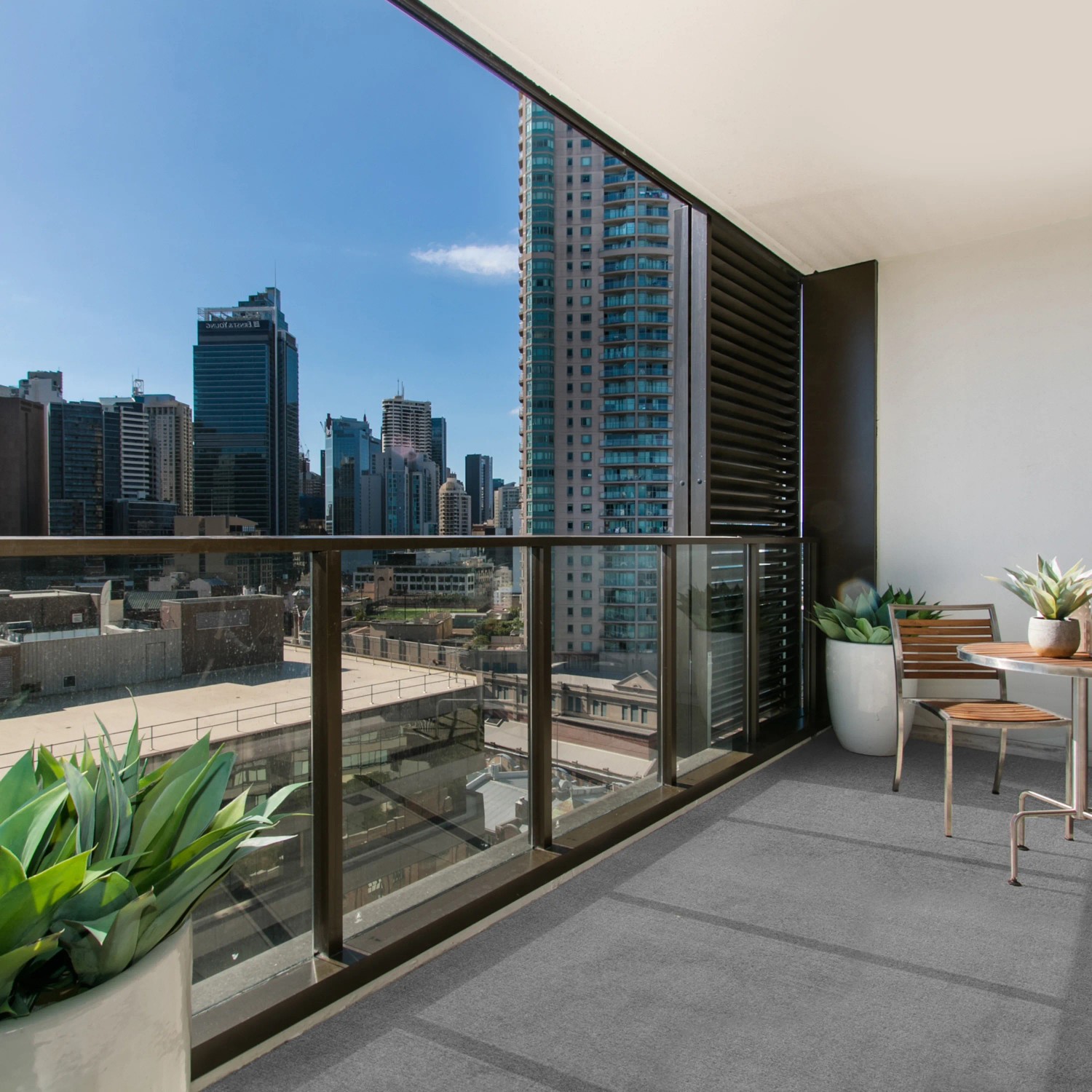 Heller, grauer Primaflor Rasenteppich Comfort (4x6,5m) auf einem Balkon mit Stadtblick.