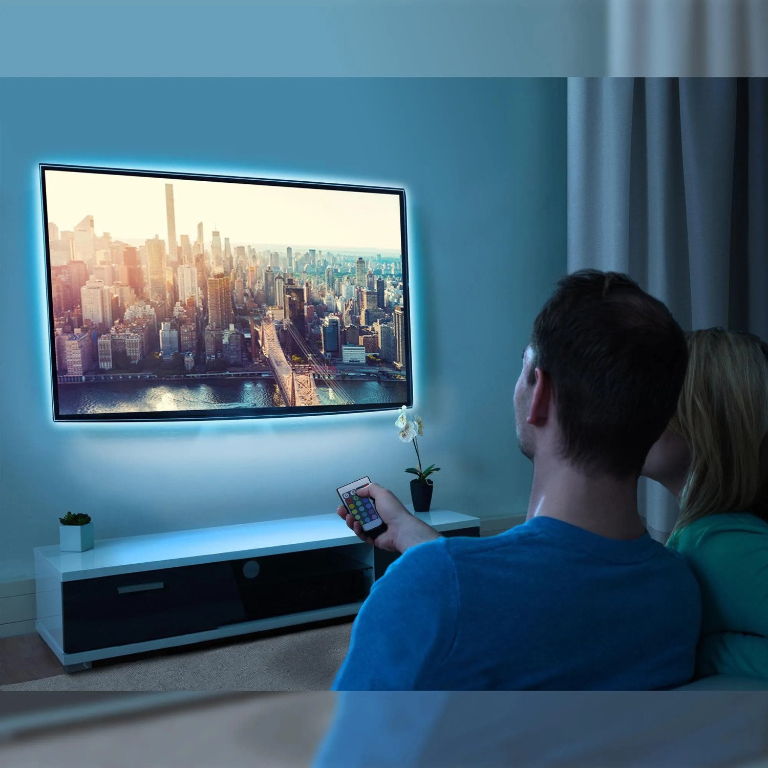 TV mit Brilo LED-Strip RGB Beleuchtung, gesteuert per Fernbedienung für Farbwechsel und Dimmfunktion.