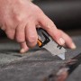 Fiskars Universal-Klappmesser CarbonMax im Einsatz: Hand schneidet Material mit dem Messer.