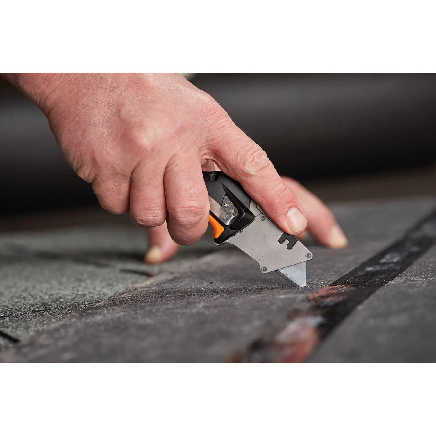 Fiskars Universal-Klappmesser CarbonMax im Einsatz: Hand schneidet Material mit dem Messer.