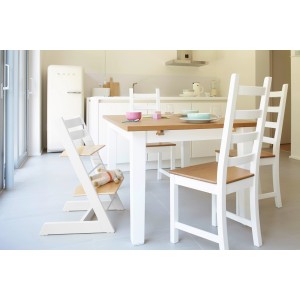 Esstisch mit weißen Beinen und Holzplatte, dazu passende Stühle und ein Kinderhochstuhl.