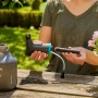 Gardena EasyPump Pumpsprüher 1 l mit Zubehör in der Hand vor Gartenkulisse.
