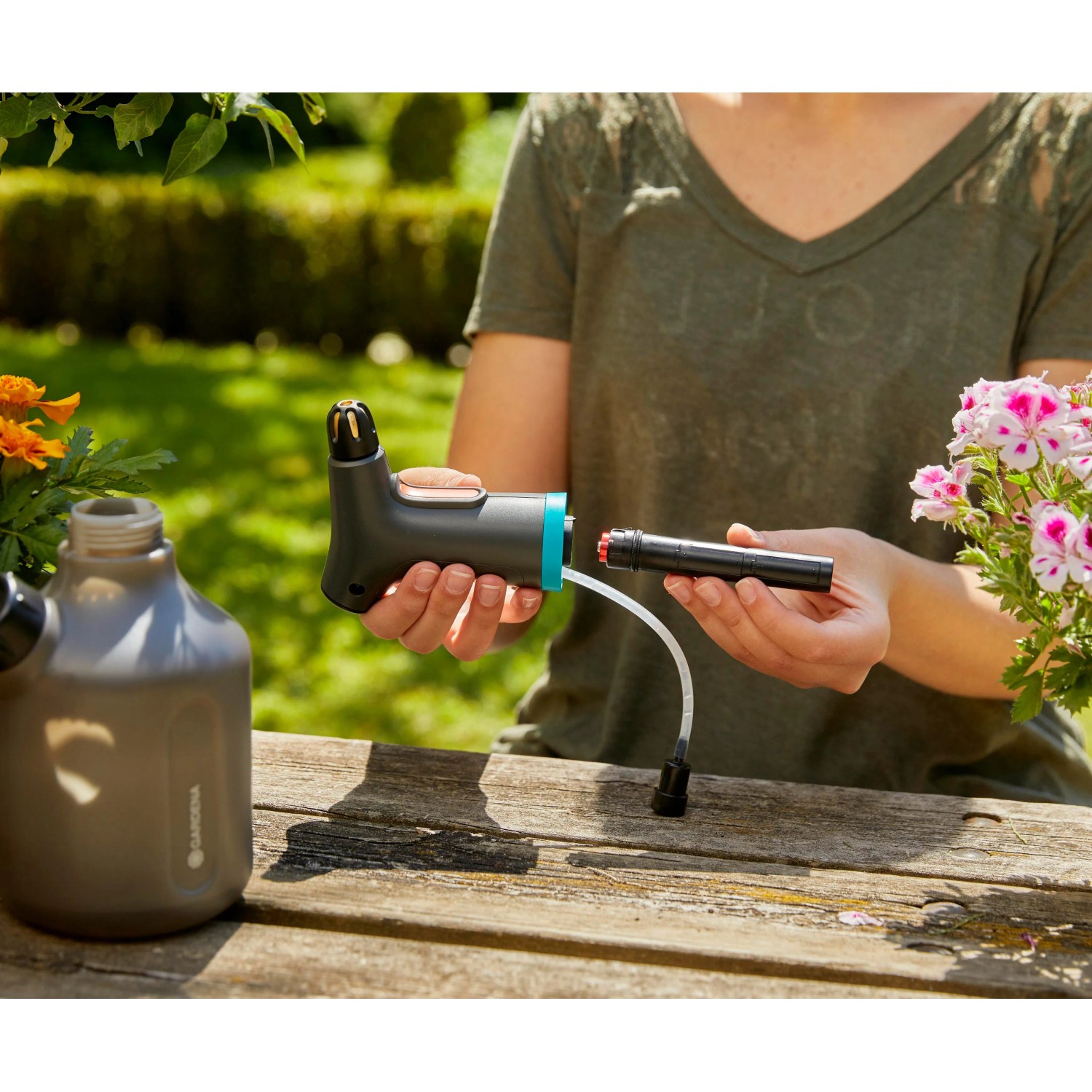 Gardena EasyPump Pumpsprüher 1 l mit Zubehör in der Hand vor Gartenkulisse.