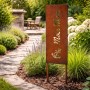 Rostbrauner Gartenstecker aus Eisen mit "Moin Moin" Schriftzug und Anker im Beet. Wetterfeste Gartendeko.