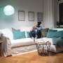Frau auf Sofa mit Osram E27 LED Lampe in Glühlampenform, dimmbar mit Fernbedienung.