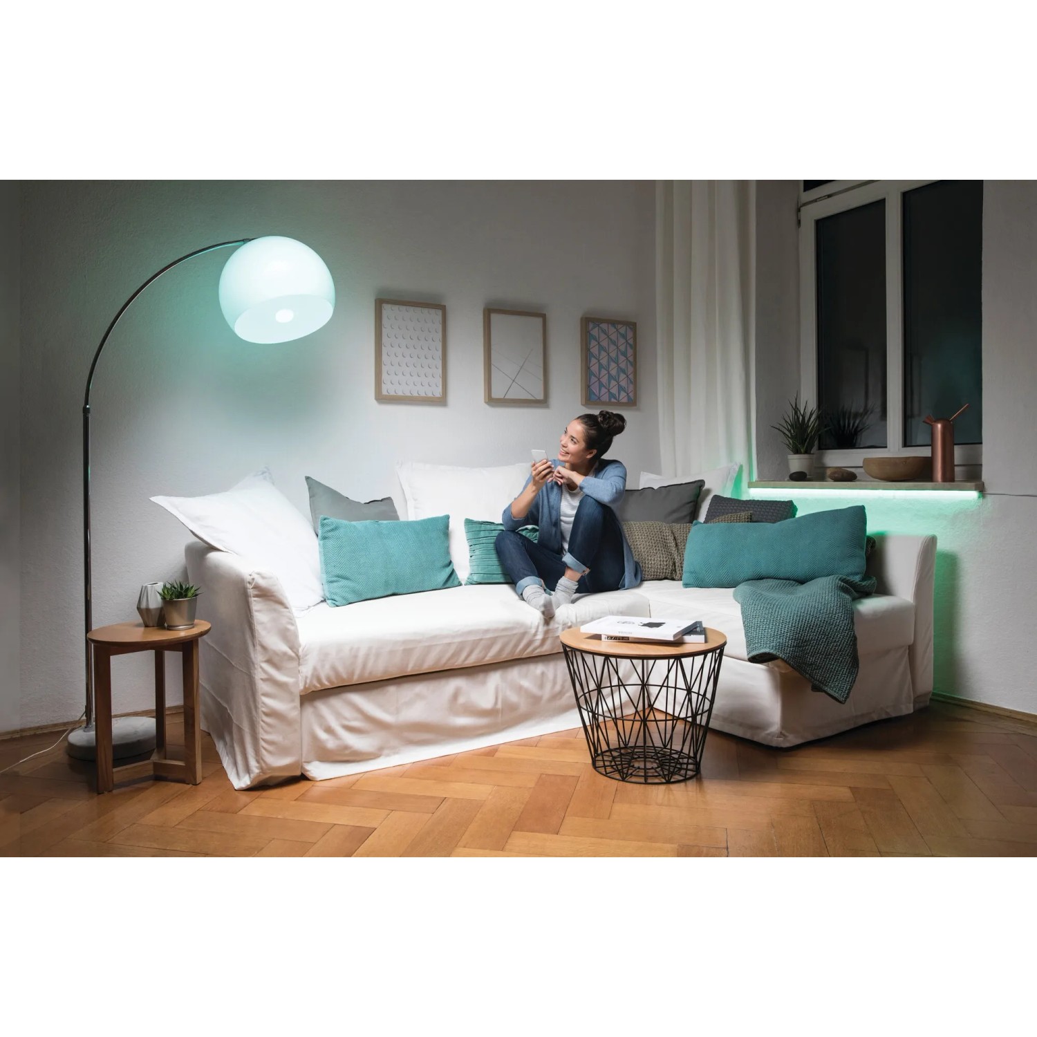 Frau auf Sofa mit Osram E27 LED Lampe in Glühlampenform, dimmbar mit Fernbedienung.