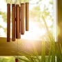 Braunes Bambus Windspiel im Tempel-Design mit Röhrchen, hängt vor sonnigem Fenster. Dekorative Figur für Garten & Balkon.