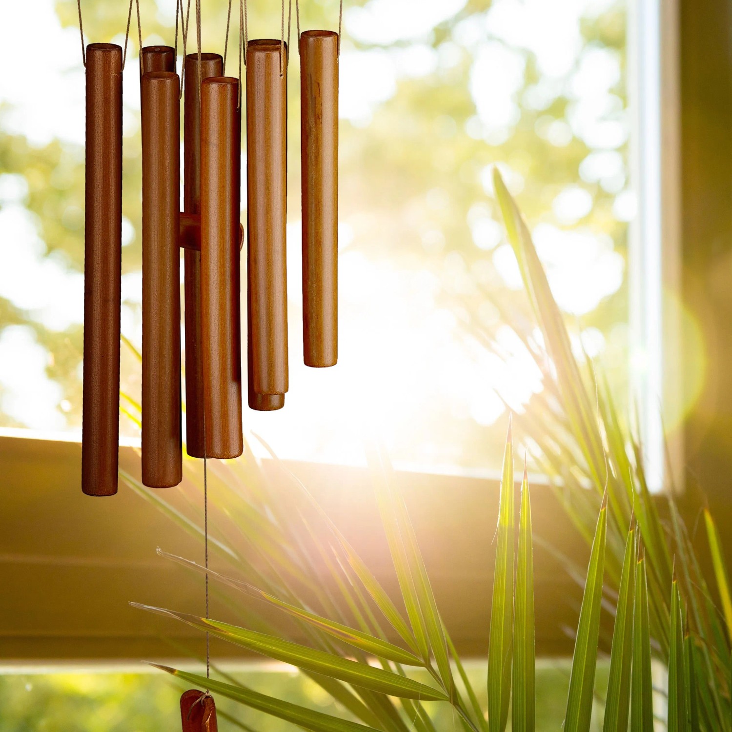 Braunes Bambus Windspiel im Tempel-Design mit Röhrchen, hängt vor sonnigem Fenster. Dekorative Figur für Garten & Balkon.
