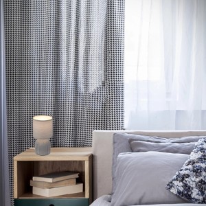 Graue Brilo Tischleuchte Ino mit Keramikfuß und Stoffschirm auf Nachttisch.