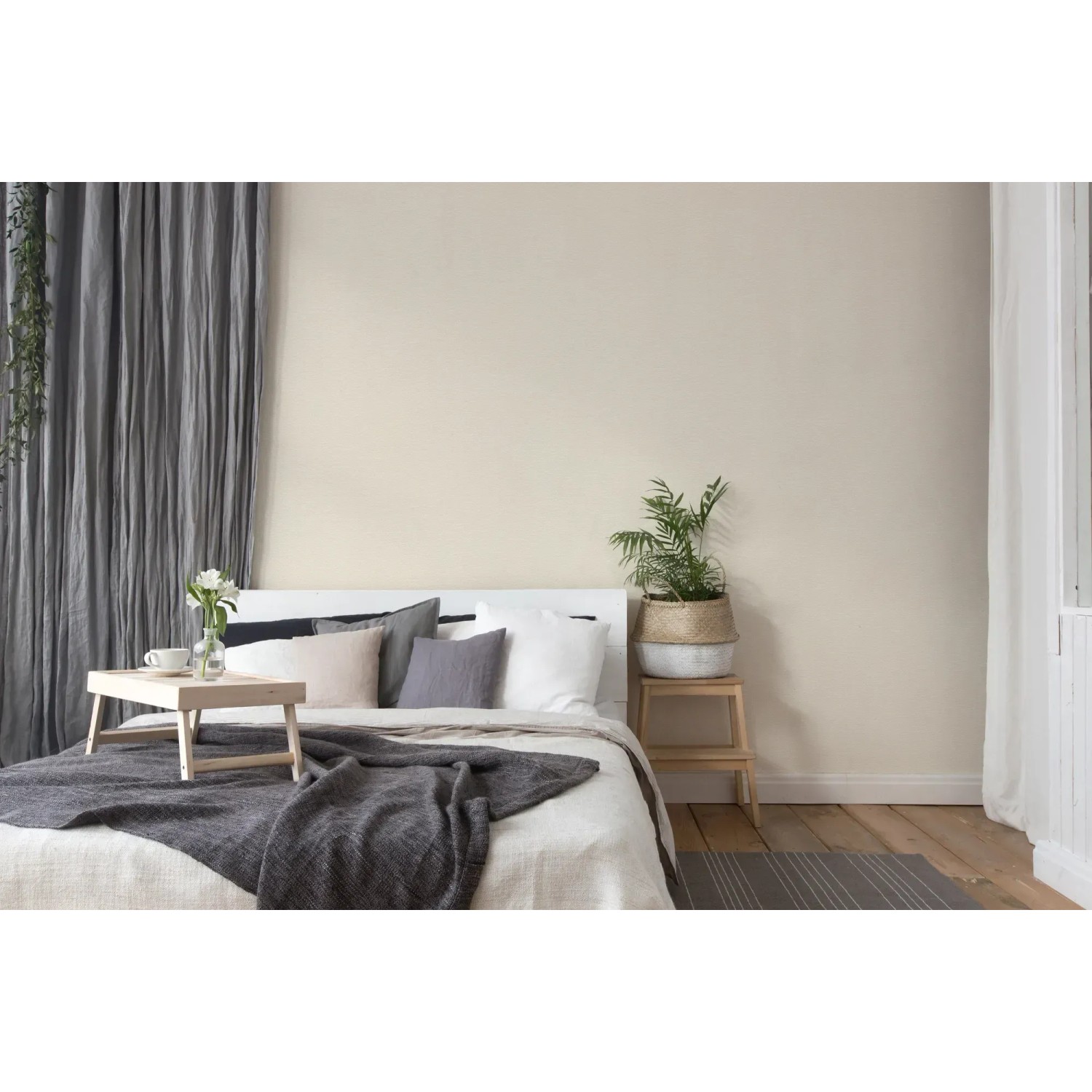 Schlafzimmer mit creme-weißer Vliestapete Uni Matt Strukturiert FSC® an der Wand.