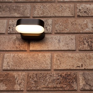 Ovale, drehbare LED Außenwandleuchte in Schwarz an einer Backsteinwand.