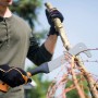 Mann entastet Ast mit Fiskars WoodXpert XA3 Machete. Gartensäge mit gebogener Klinge.