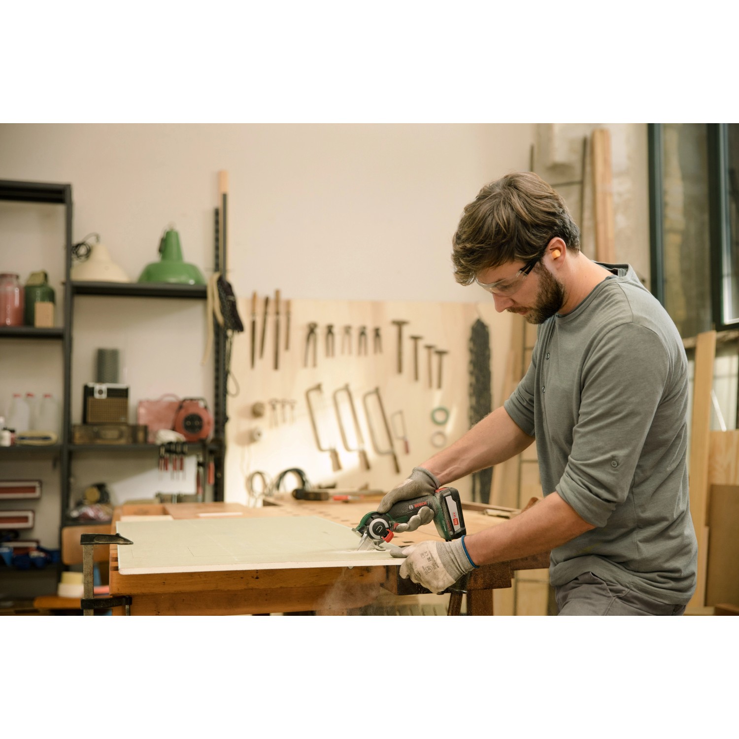 Mann sägt Holz mit Bosch Akku-Säge AdvancedCut 18. Stichsäge mit NanoBlade Technologie im Einsatz.