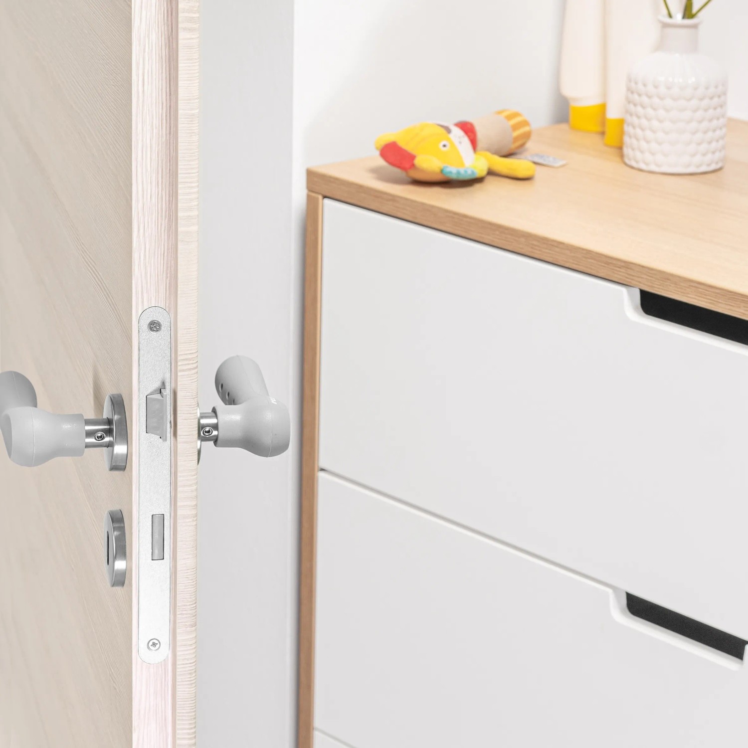 Grauer Reer Türgriffschutz HandleGuard aus Silikon, 2er-Set, montiert an einer Tür.