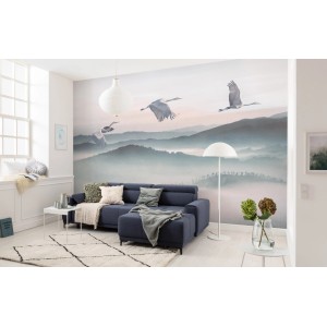 Komar Vlies Fototapete Mystic Cranes im Wohnzimmer mit Kranich-Motiv und Bergen.