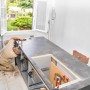 Monteur beim Aufbau einer Respekta Küchenzeile mit grauer Arbeitsplatte und Spülbecken-Ausschnitt.