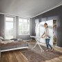 Frau bügelt Wäsche auf dem Leifheit Bügeltisch Fashion M Plus im Schlafzimmer.