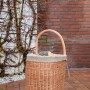 Kaminholzwagen aus Weide mit Jute-Auskleidung und Rädern vor einer Hauswand.
