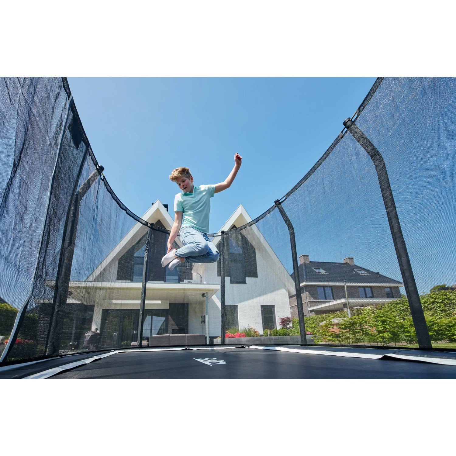 Schwarzes Salta Premium Ground Trampolin 366x244 cm mit springendem Kind im Garten.