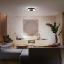 Schwarze Philips Hue Infuse L Deckenleuchte mit Farbwechsel im Wohnzimmer.