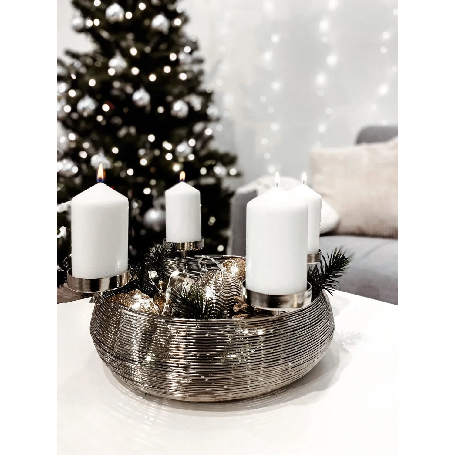 Silberner Kobolo Adventskranz aus Metall mit Schale und vier weißen Kerzen vor Weihnachtsbaum.