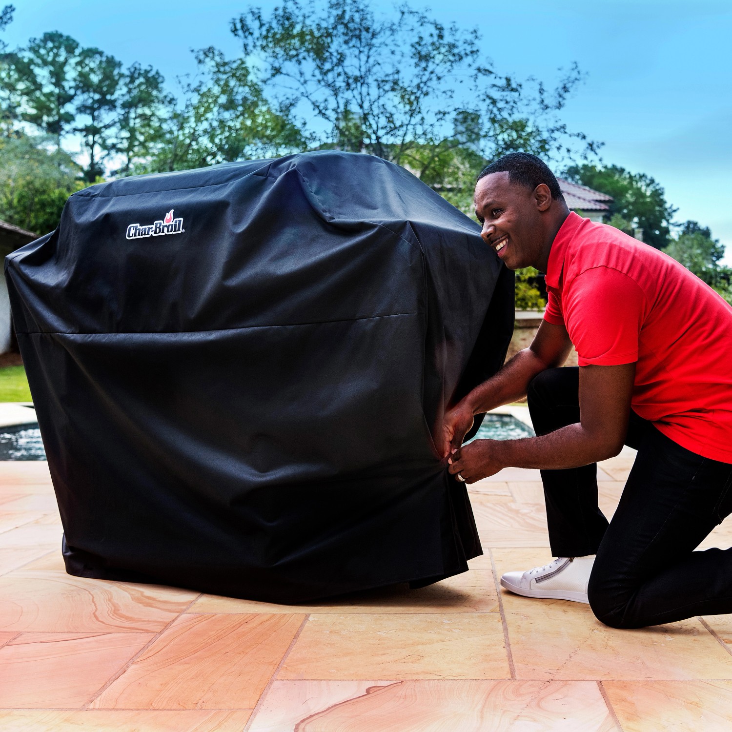 Schwarze Char-Broil Grillabdeckung für 3-4 Brenner Gasgrill, mit Person.
