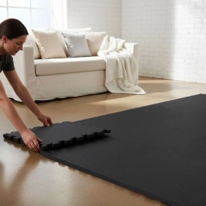 Person verlegt schwarze eyepower Fitnessmatten (9-teilig, 30x30 cm) aus EVA-Schaum als Bodenschutz im Home Gym.