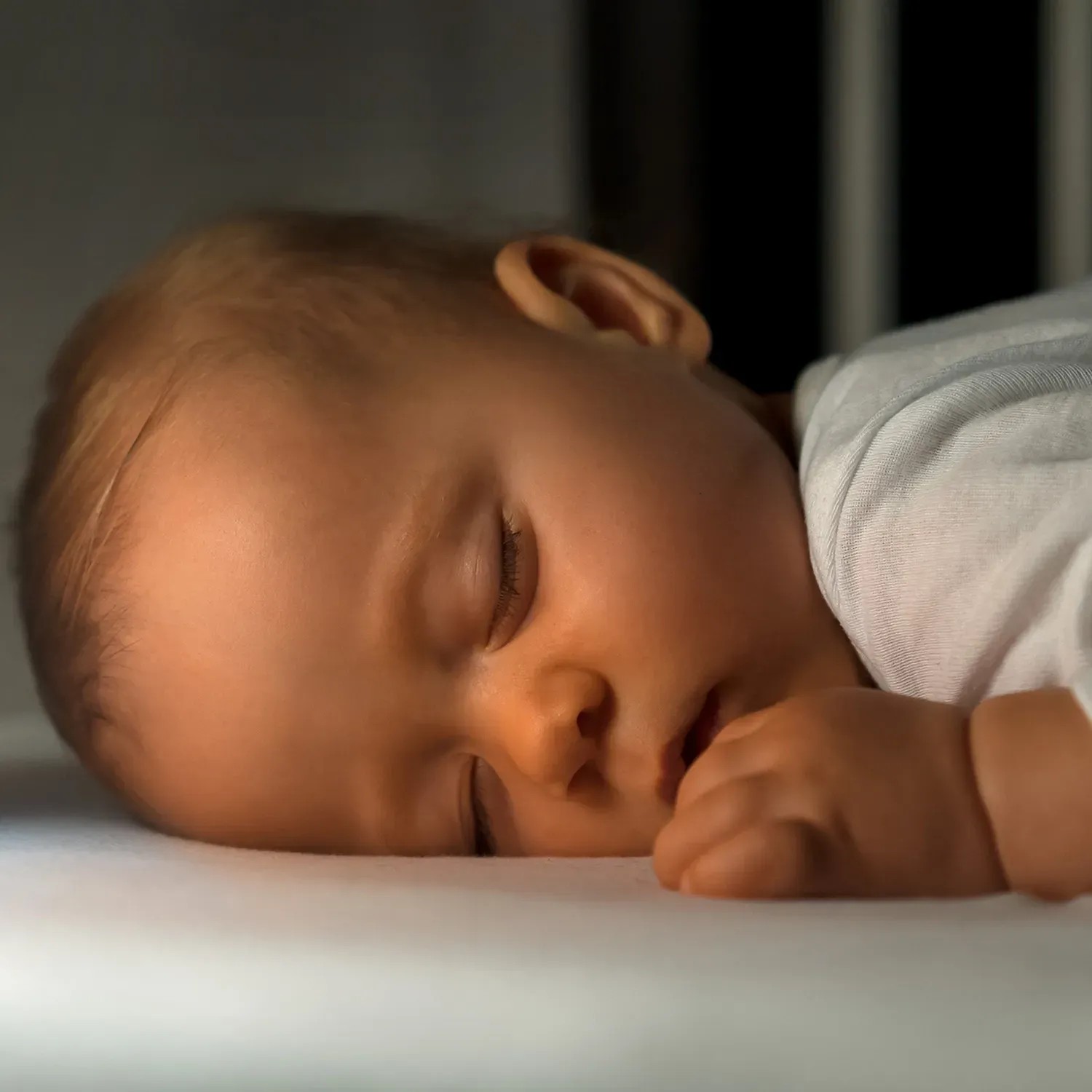 Schlafendes Baby im Gitterbett, beleuchtet durch Reer Nachtlicht MyBabyLight - Mond.