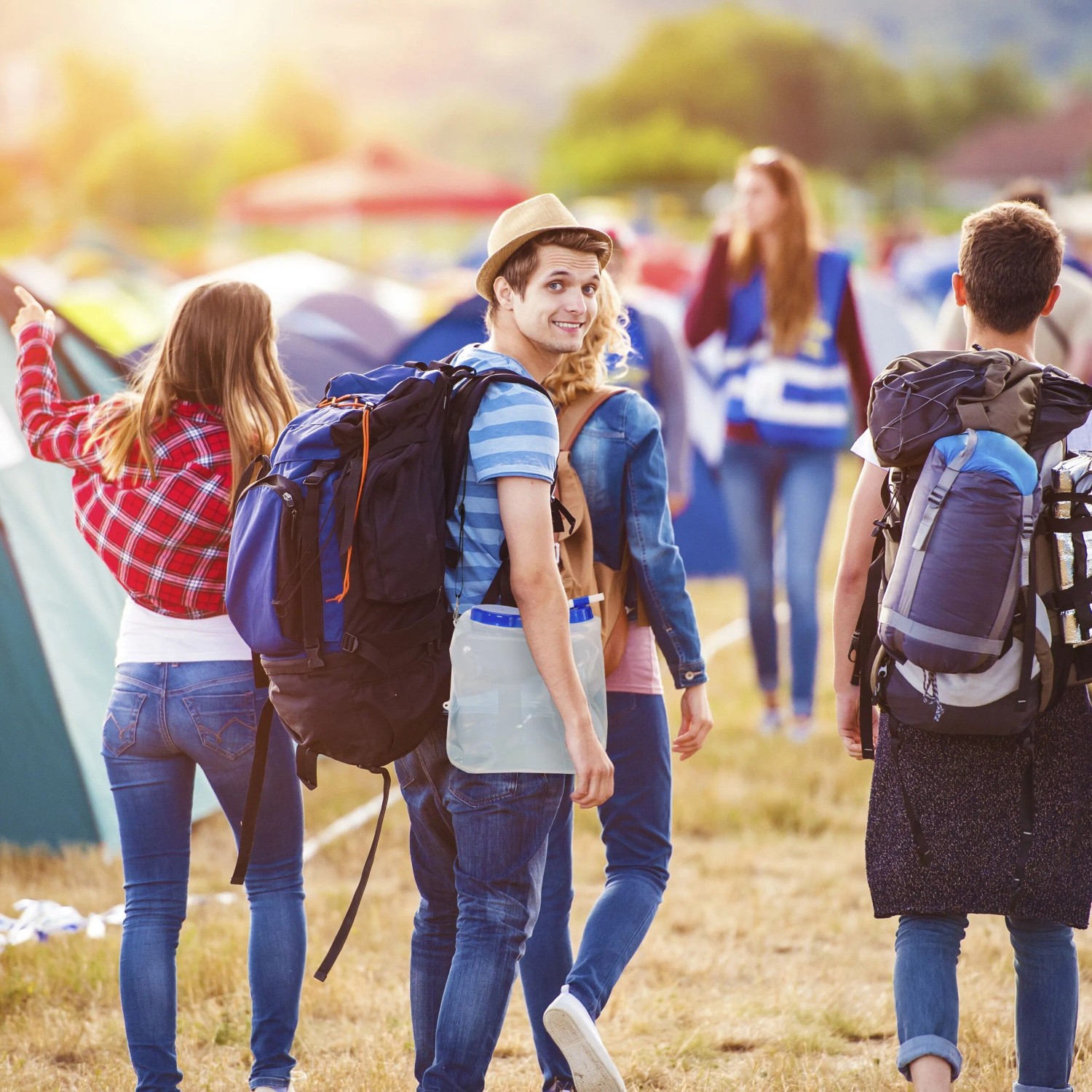 Mann trägt transparenten blauen 15 l Faltkanister mit Zapfhahn am Rucksack auf einem Festivalgelände. Perfekt für Camping & Outdoor.