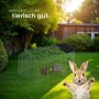 Schwarzes Tectake Freilaufgehege für Kaninchen mit Sonnenschutz im Garten.