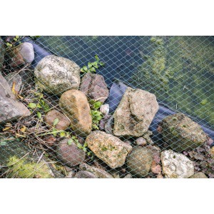 Dunkelgrünes Aquagart Teichnetz über einem Teich mit Steinen am Rand.