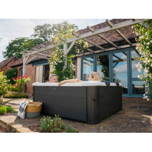 MSpa Frame Whirlpool Oslo mit Hydromassage im Garten, zwei Personen entspannen im Outdoor-Whirlpool.