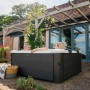 MSpa Frame Whirlpool Oslo mit Hydromassage im Garten, zwei Personen entspannen im Outdoor-Whirlpool.