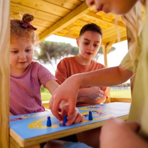 Kinder spielen Brettspiel im roten Wickey Spielturm Disney Story Klettergerüst mit Rutsche.