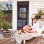 Anthrazitfarbener tesa Magnetvorhang an Terrassentür, Mann und Hund entspannen auf Liege.