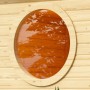 Rundes Karibu Saunafenster aus naturbelassenem Holz mit Klarglas für mehr Licht in der Sauna.